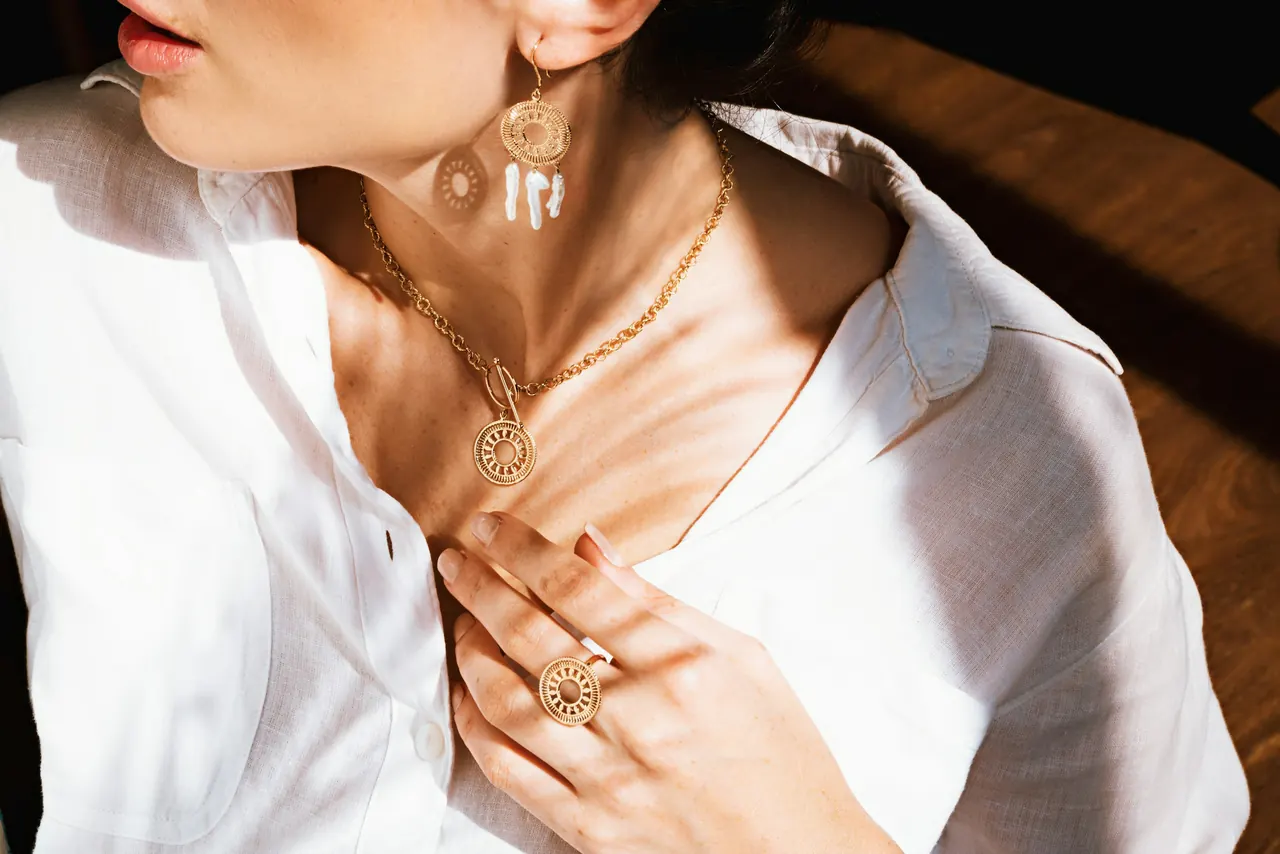 A woman in a white shirt wearing a fine gold necklace