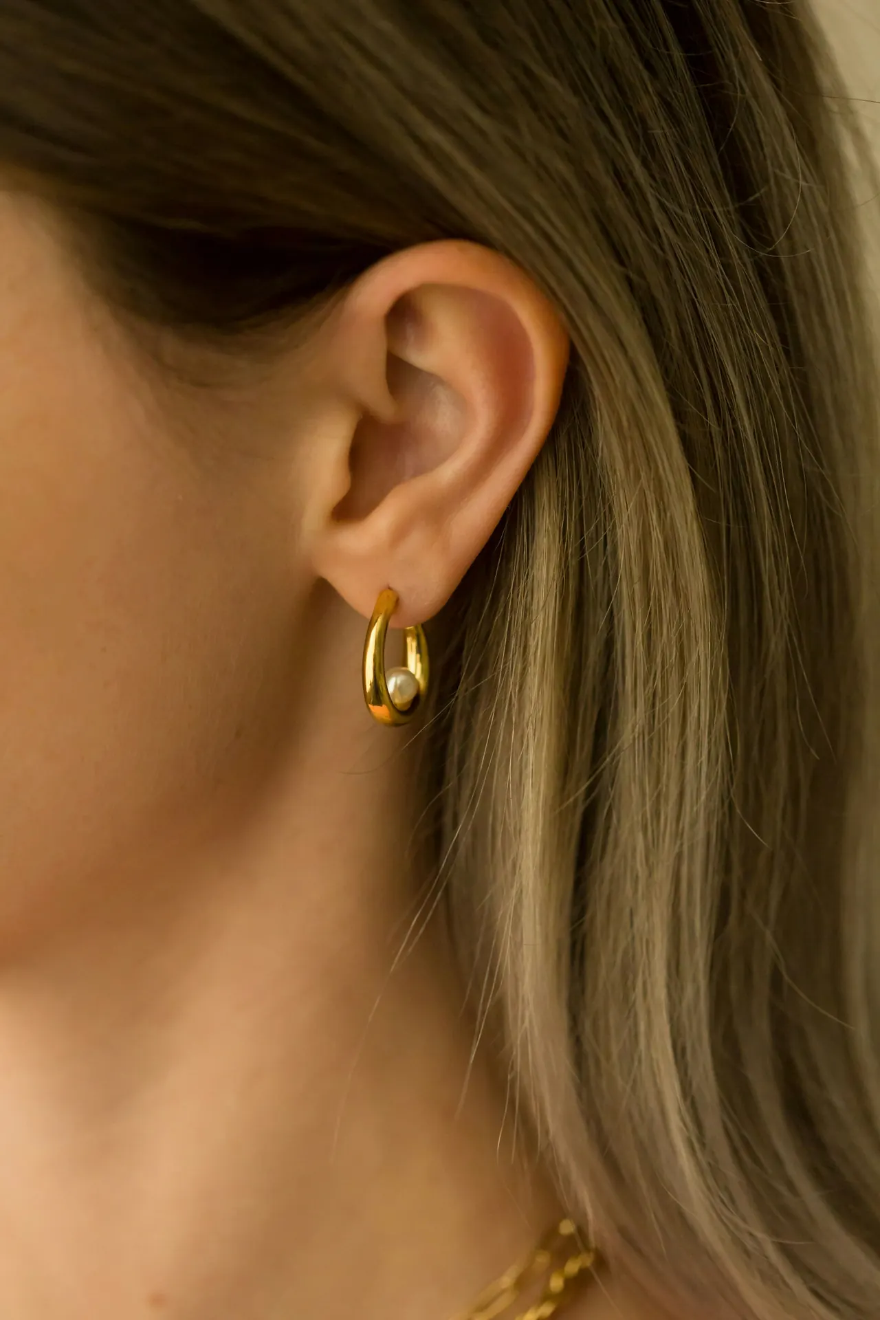 A close-up of gold earrings being worn