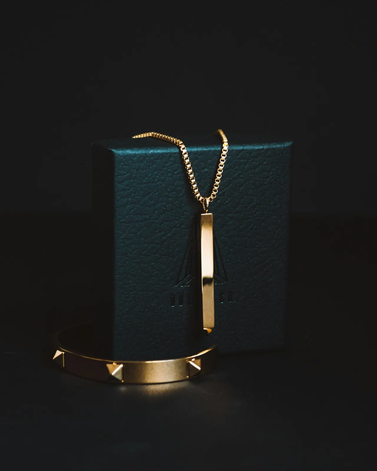 A gold pendant necklace in low light